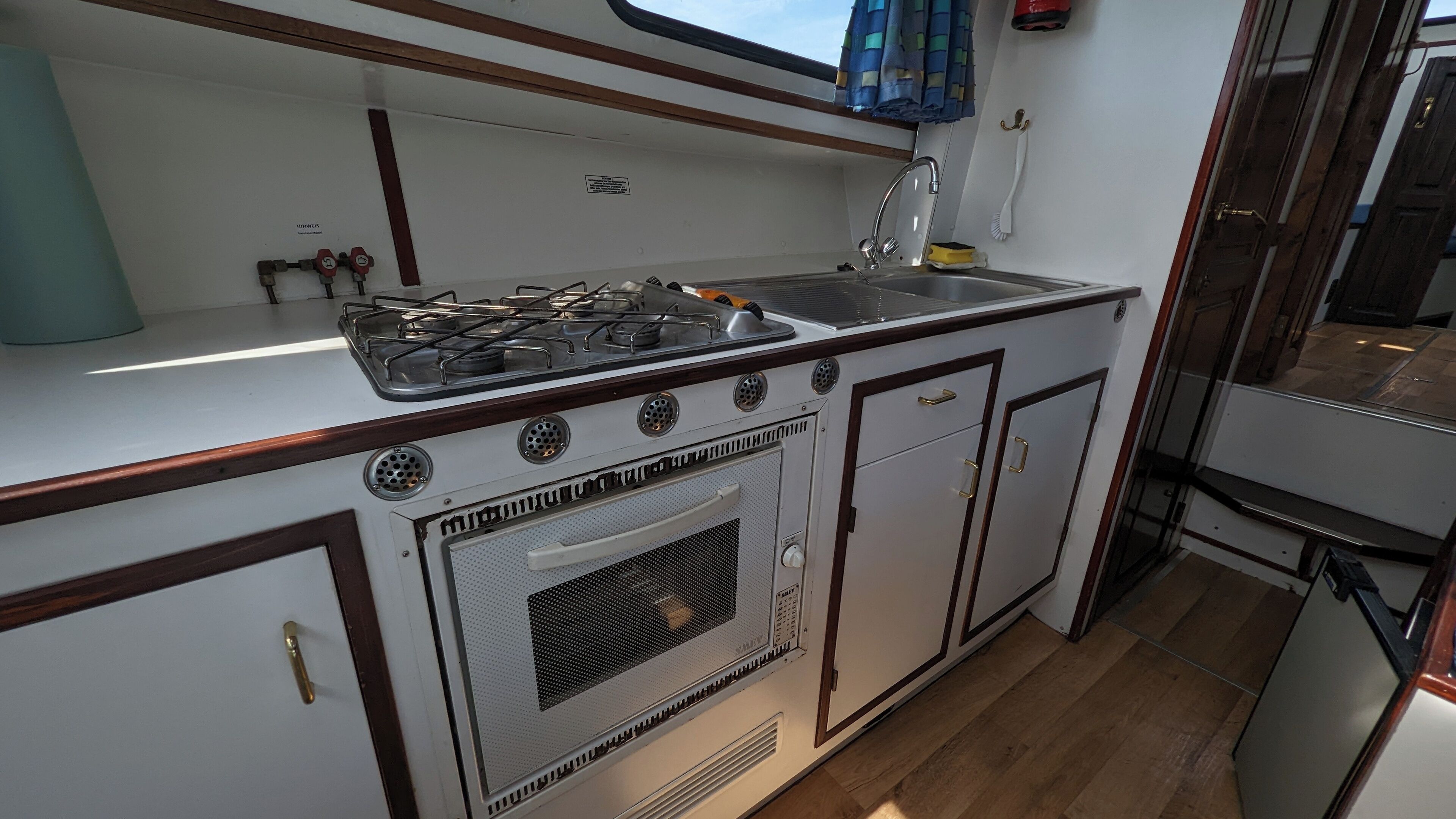 A compact kitchen with a gas stove, sink, and storage cabinets.