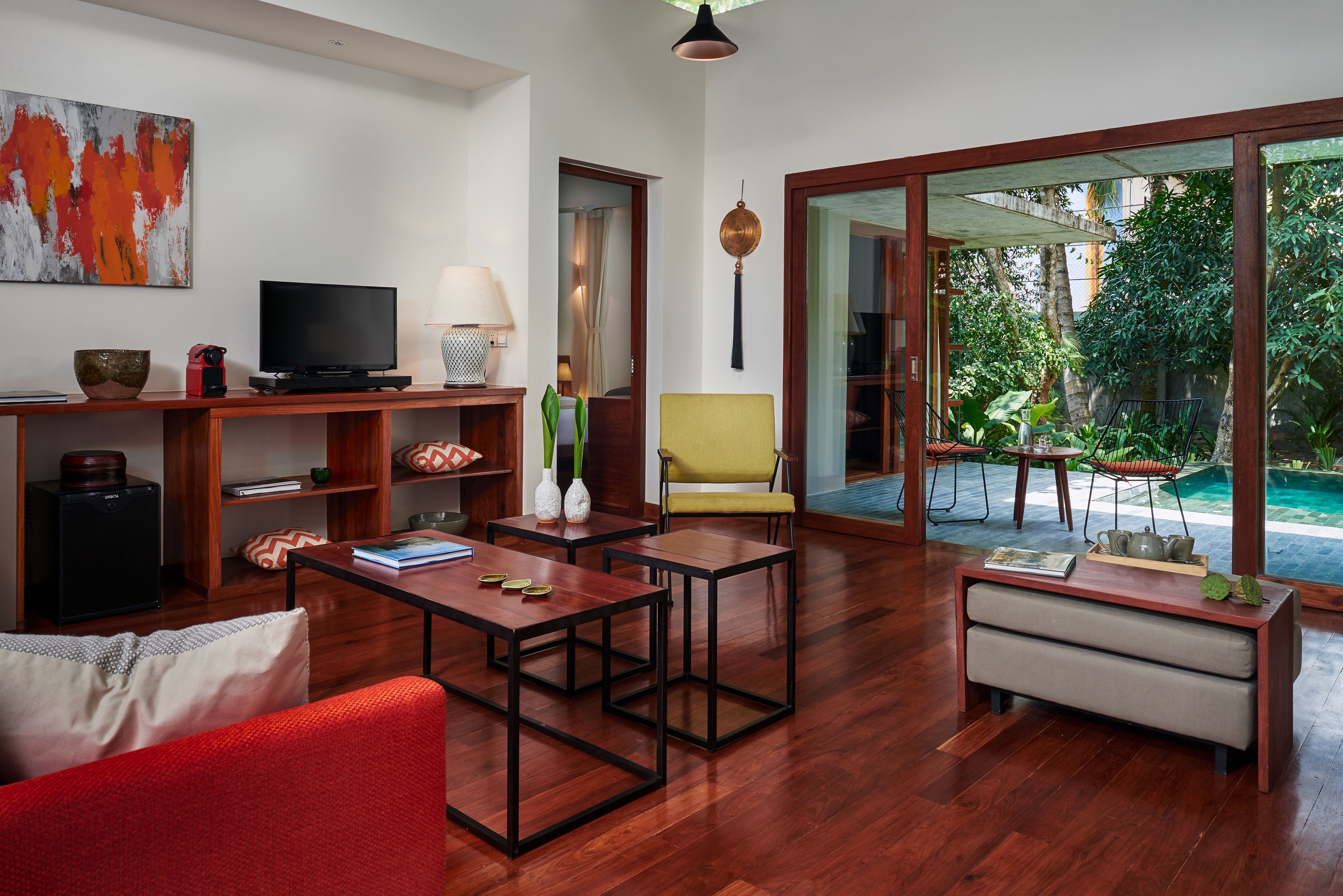 A spacious living area with a wooden floor, a television, books, and a yellow chair.