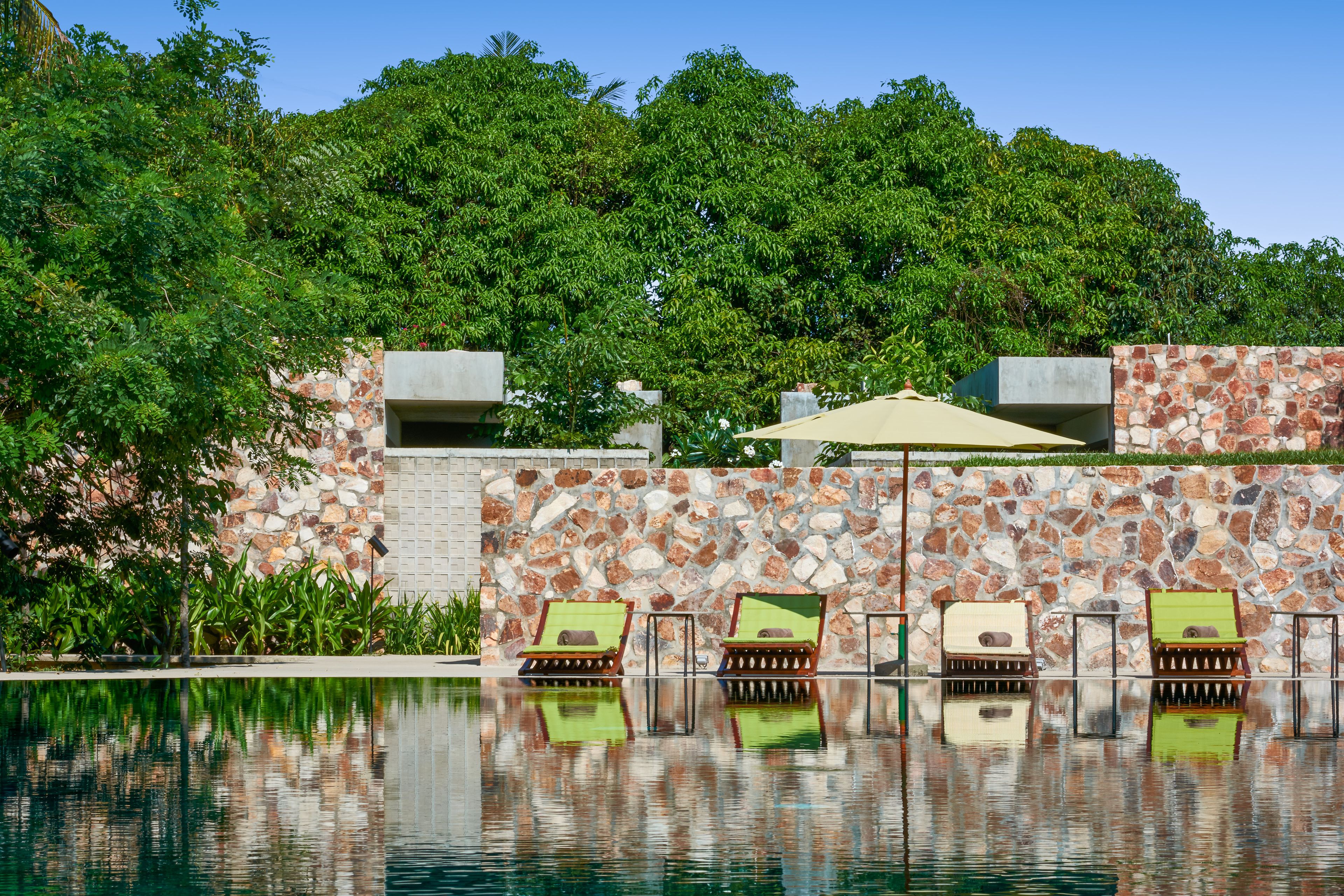 Uma área de piscina com espreguiçadeiras e um muro de pedra.