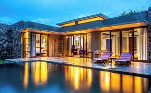 Una casa moderna con piscina, amplios ventanales y mobiliario de exterior.