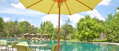 A pool area with lounge chairs and a large umbrella.