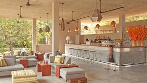 Amplia sala de estar con diversas opciones de asientos, un bar con taburetes y vistas al exterior.