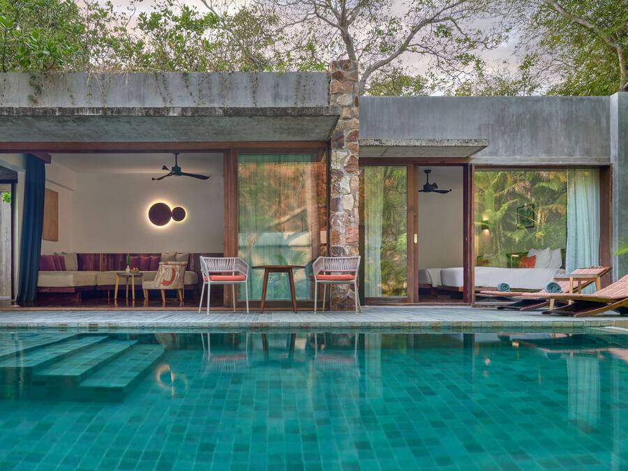 Una villa moderna con piscina, que incluye un comedor, un dormitorio con vistas a la piscina y un salón independiente con asientos.