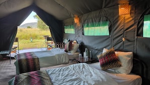 A tent with two beds, a table, chairs, and a view of the outdoors. - Kananga Special Tented Camp (Serengeti)