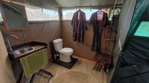 Un baño pequeño y funcional con lavamanos, inodoro y un perchero para ropa.