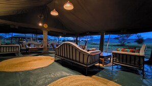 A tented outdoor lounge area with seating arrangements and hanging lights. - Kananga Special Tented Camp (Serengeti)