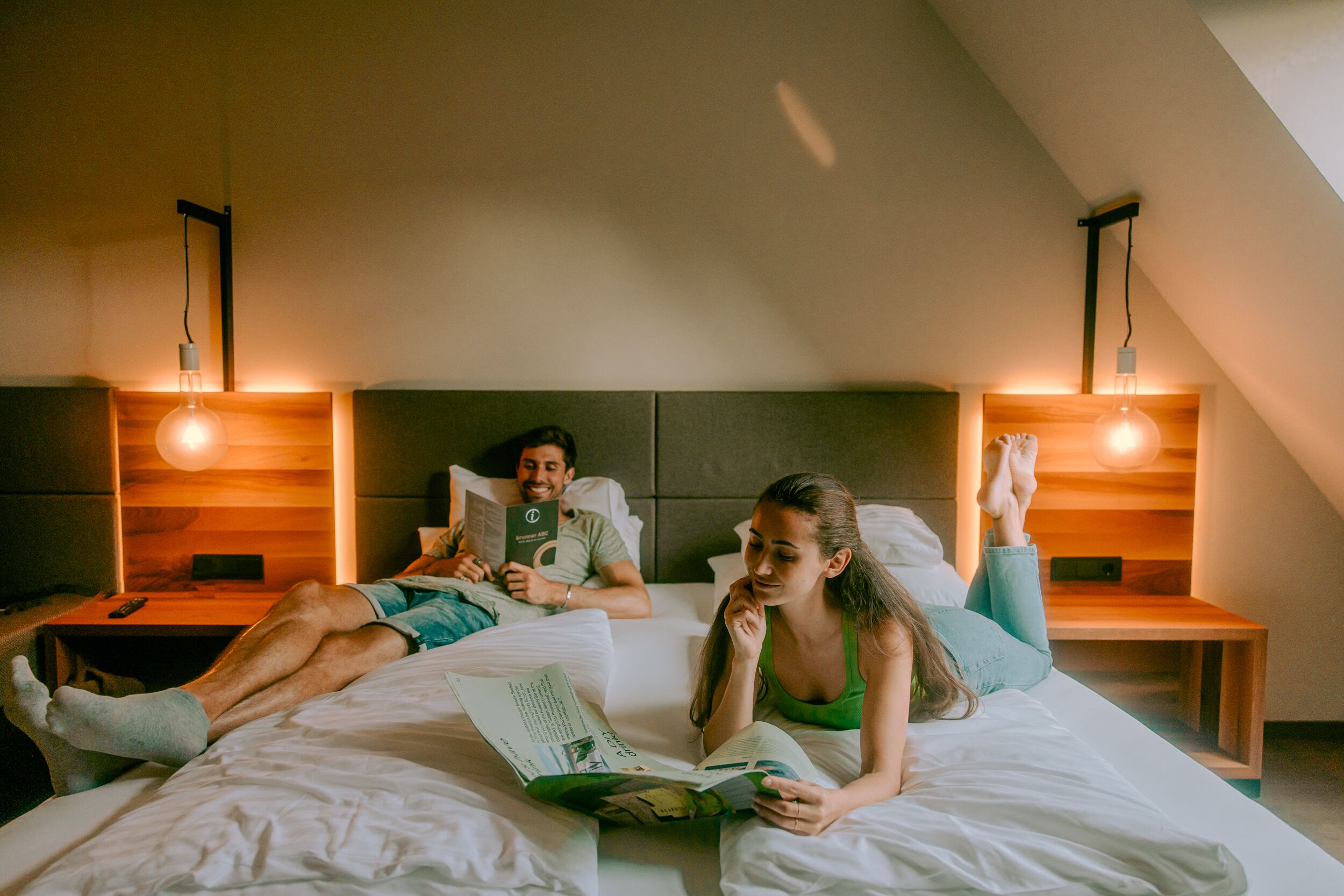 A room with a bed, two bedside tables, and a slanted ceiling.