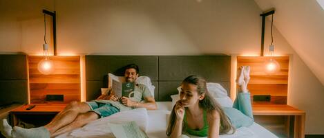 A room with a bed, two bedside tables, and a slanted ceiling.