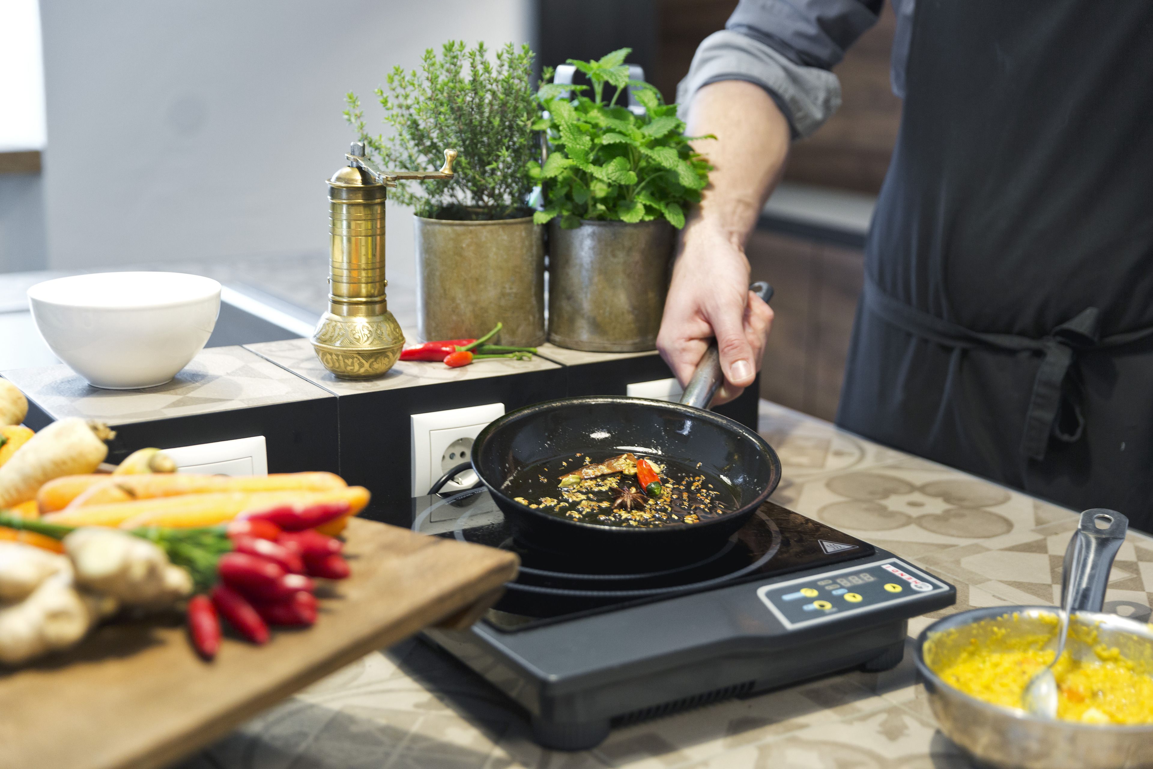 Una encimera de cocina con una sartén, verduras y un bol.
