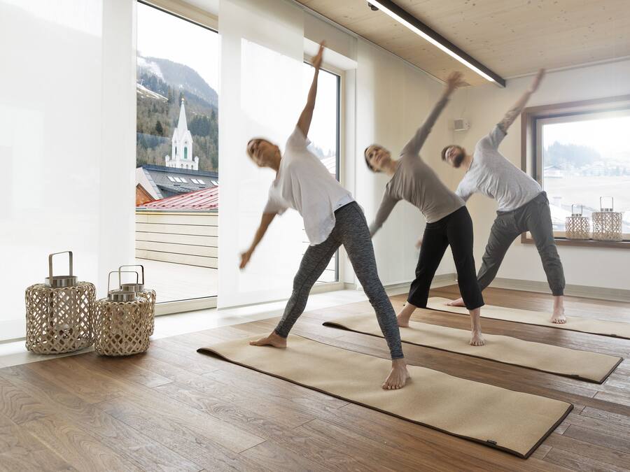 Un estudio de yoga con amplios ventanales, pisos de madera y esterillas.