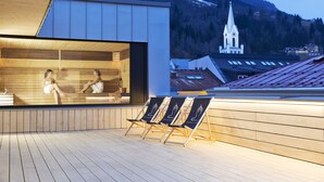 A modern spa with wooden floors and a view of a church and mountains in the background. - Stadthotel brunner (Schladming)