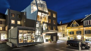 A modern building with a glass facade, multiple windows, and a visible staircase leading to an upper level. - Stadthotel brunner (Schladming)