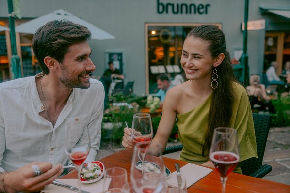 Two people dining outdoors at a restaurant with a visible sign 'brunner'.