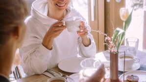 A dining area with a table set for two, featuring a coffee cup, a bowl of soup, and a plate of food. - Stadthotel brunner (Schladming)