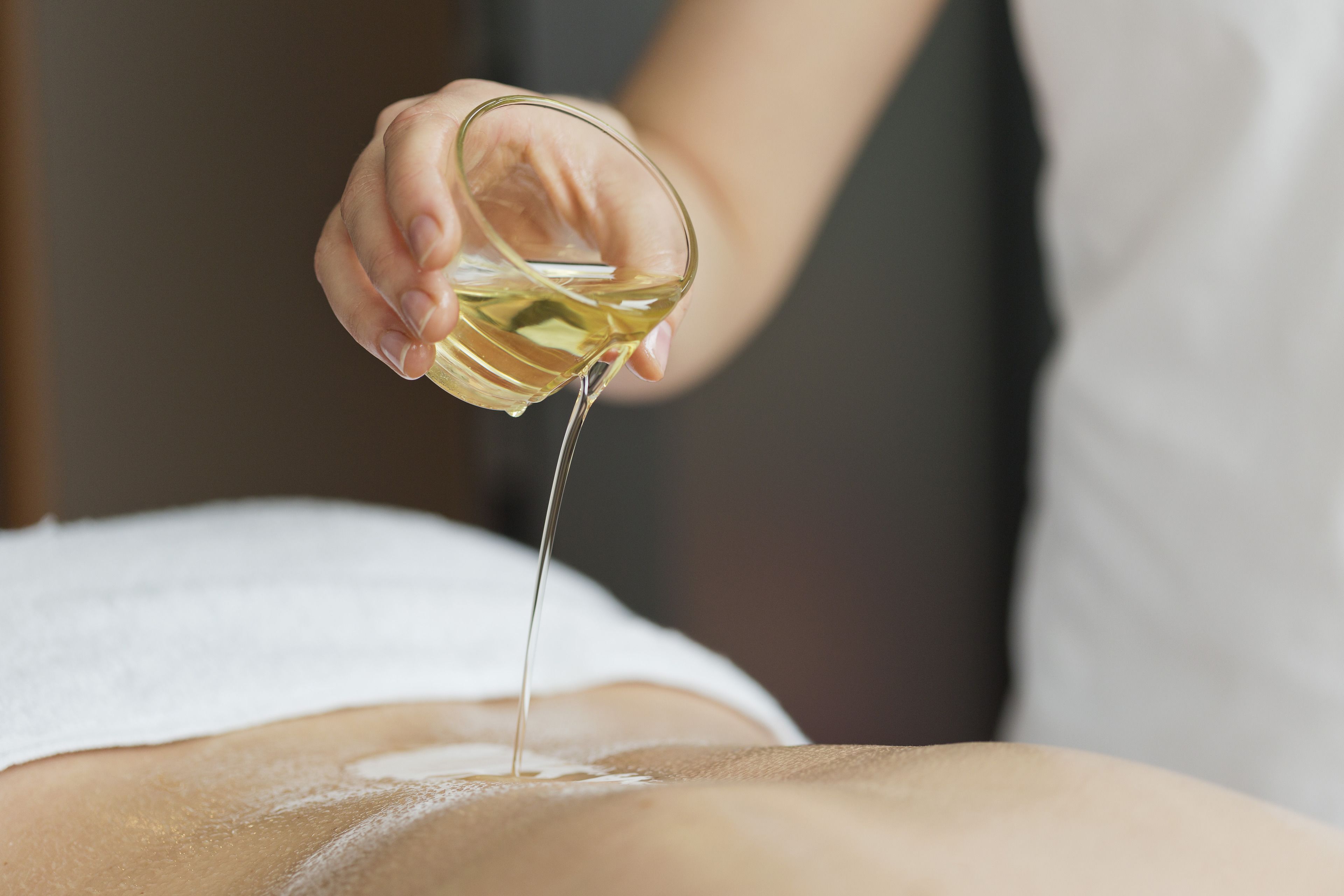 A person pouring oil on another person's back.