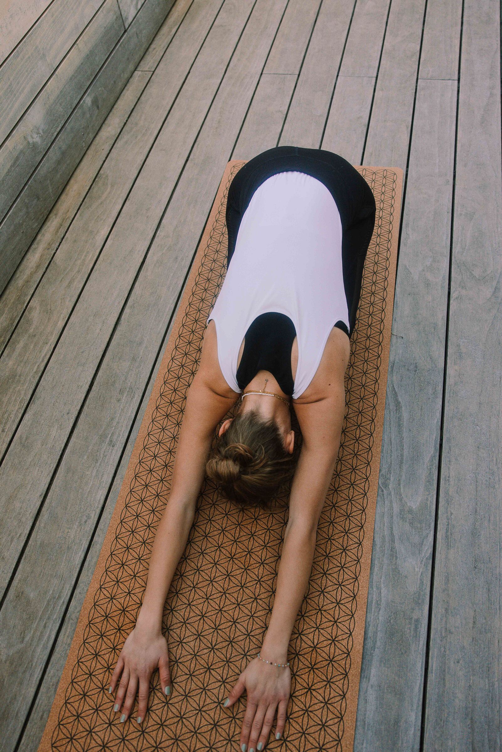 Eine Person liegt auf einer Yogamatte auf einem Holzboden.