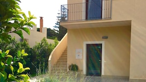 Un edificio de dos pisos con entrada pavimentada y un pequeño jardín.