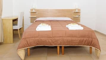 Ein ordentlich bezogenes Bett mit einer braunen Tagesdecke und zwei darauf gefalteten Handtüchern.