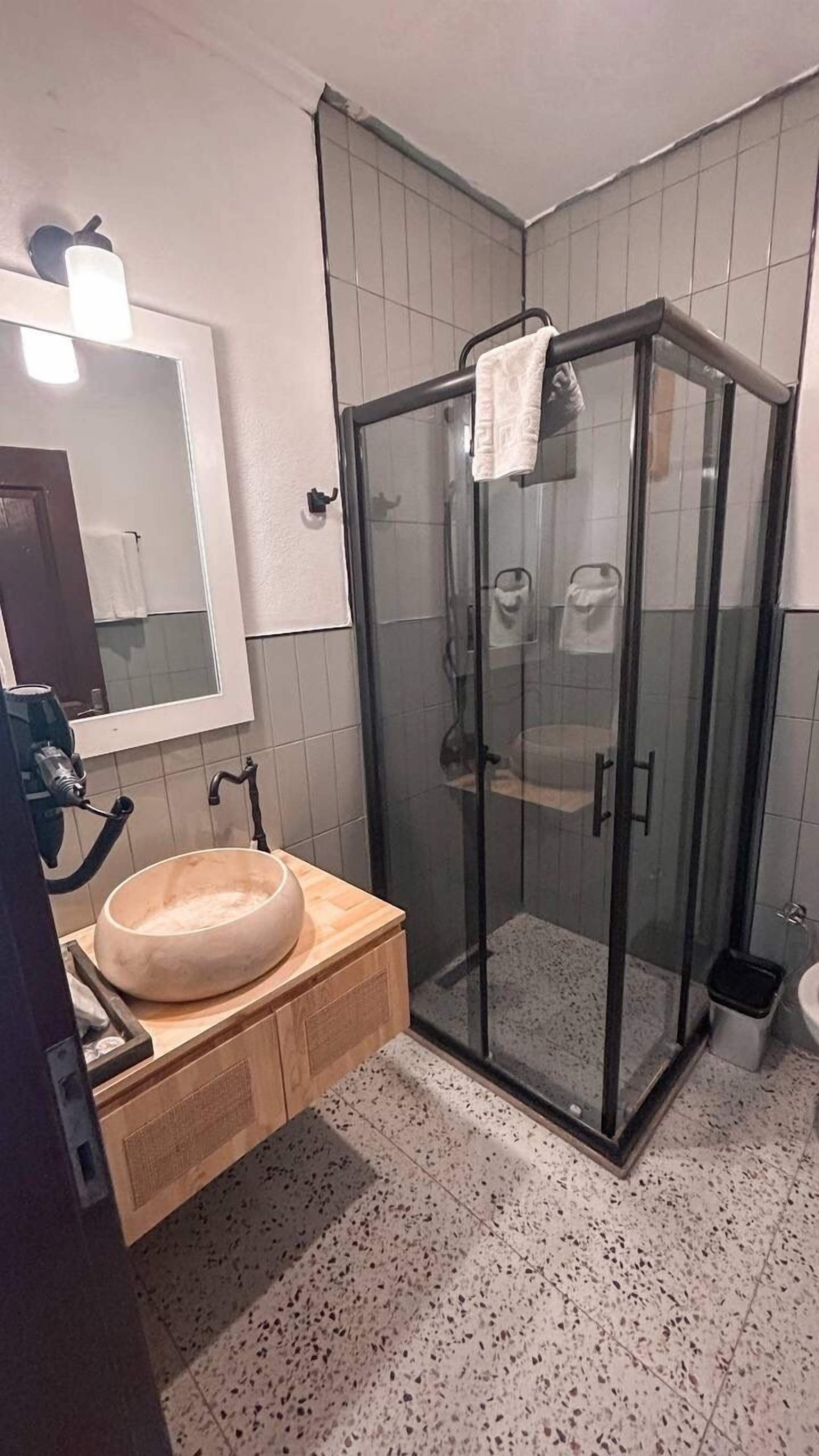 A bathroom with a glass-enclosed shower, a wooden vanity with a sink, and a mirror above the vanity.