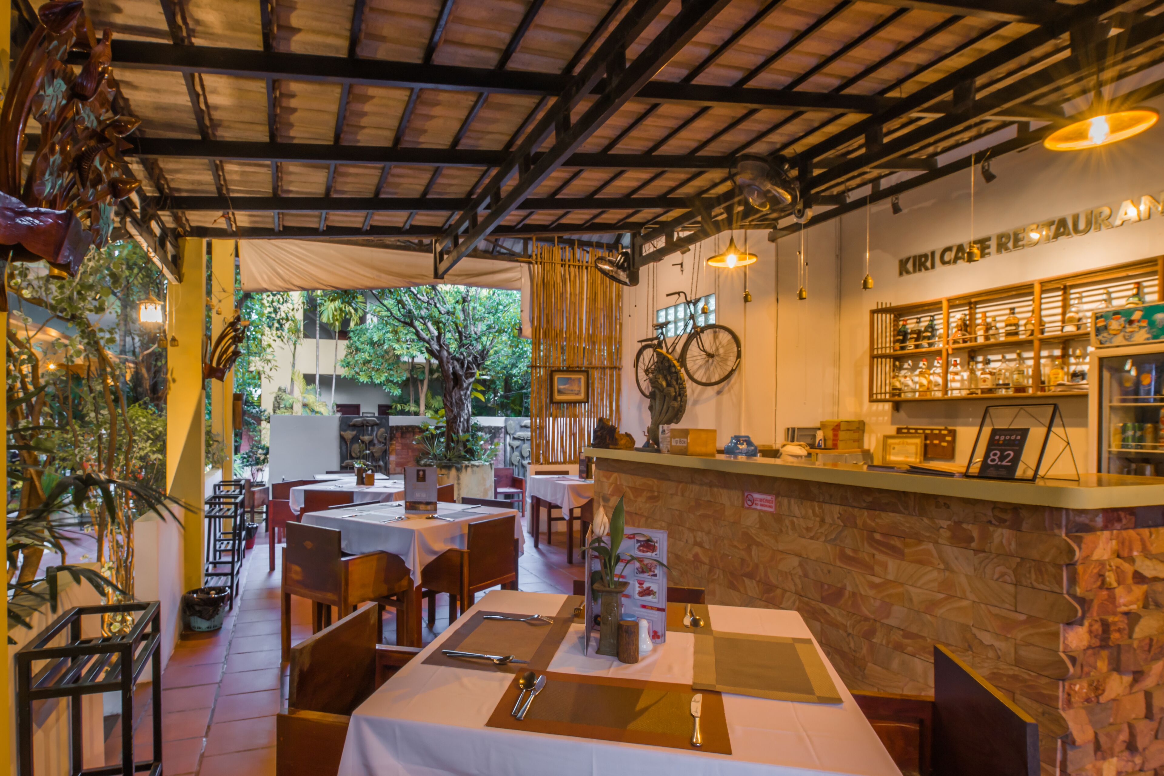 A restaurant with tables set for dining, a counter with a menu, and a view of the outdoors.