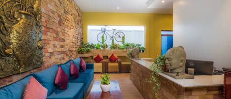 Un lobby moderno con un sofá azul, un mostrador de recepción y un ventanal con una bicicleta.
