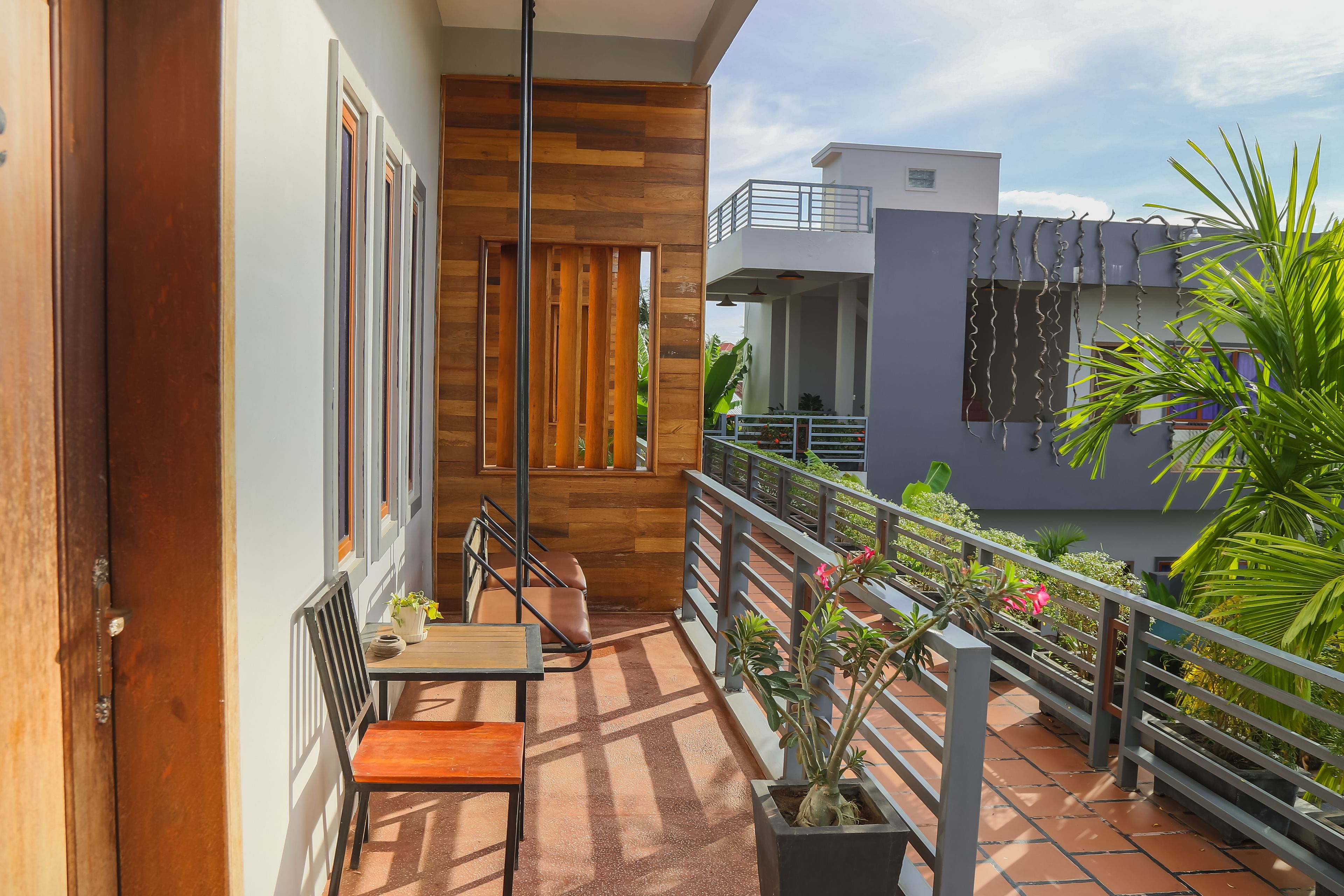 A balcony with a wooden bench, a potted plant, and a view of a neighboring building.