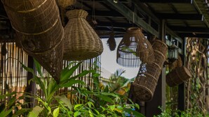 Wicker hanging lamps and green foliage in a covered outdoor area. - Indra Porak Residence Hotel (Siem Reap)