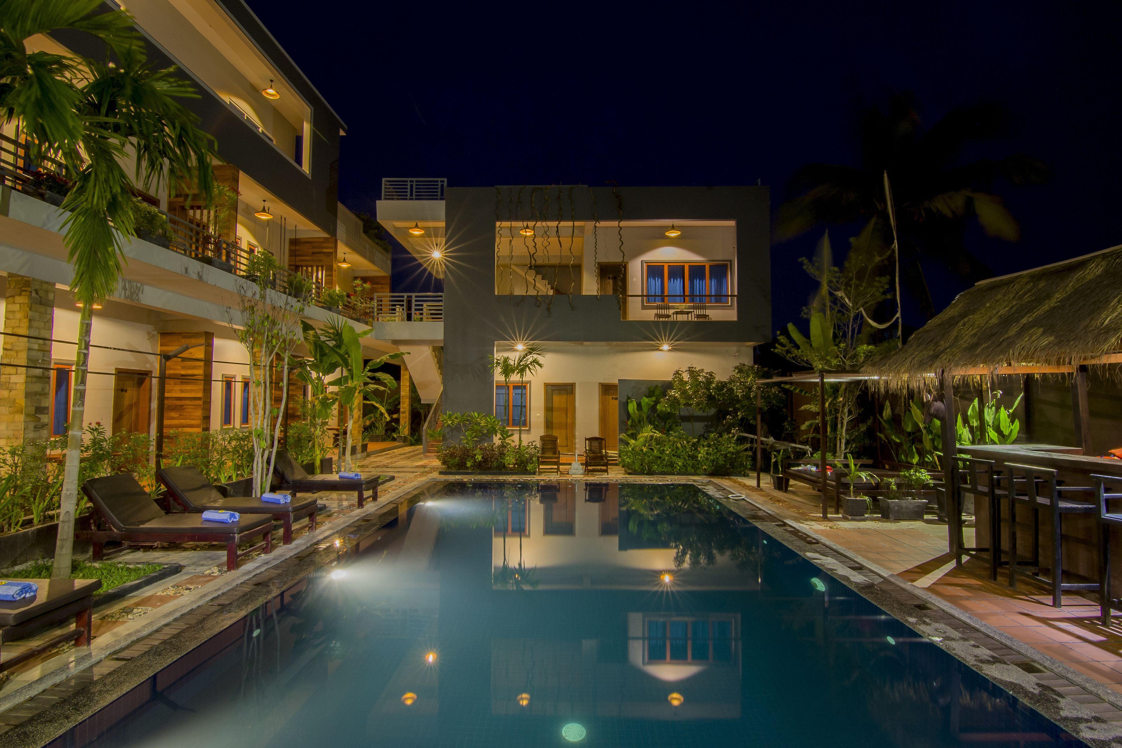 A modern hotel with a swimming pool, lounge chairs, and a bar area.