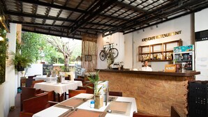 A restaurant with tables set for dining, a bar area, and a counter with a sign reading "Kiki Cafe Restaurant". - Indra Porak Residence Hotel (Siem Reap)
