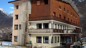 Ein mehrstöckiges Hotel mit Holzfassade, Balkonen und Blick auf schneebedeckte Berge.