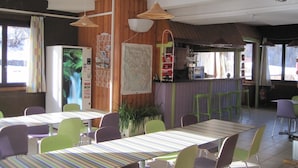 Ein Restaurant mit gestreiften Tischen und Stühlen, einem Barbereich und einem großen Fenster mit Blick nach außen.