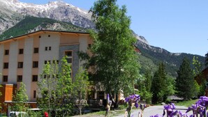 Ein Hotel mit einer Stein-Fassade, zahlreichen Fenstern und Blick auf die Berge.