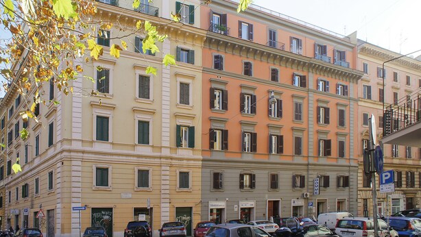 A multi-story building with a row of parked cars in front. - B&B Girovagando (Rome)