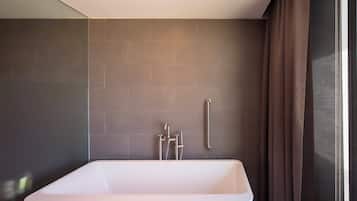 A modern bathroom with a large bathtub, a shower area, and a towel rack.