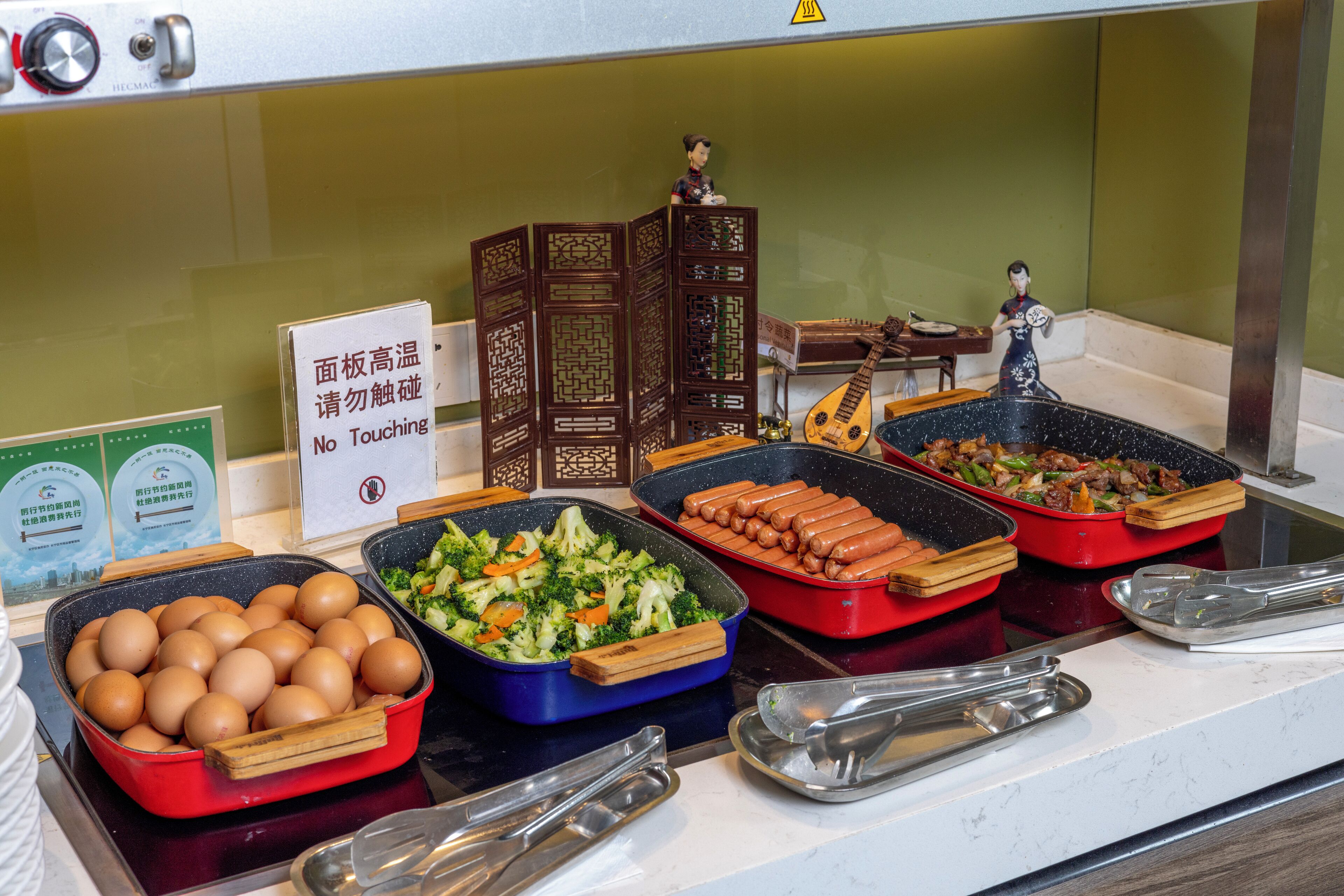 A buffet with various food items including eggs, vegetables, and hot dogs.