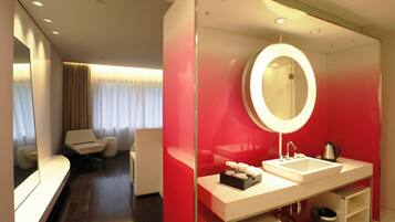 Una habitación de hotel moderna con un espejo grande, un tocador blanco y una pared de acento roja.