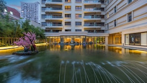 A modern hotel with a large indoor pool, surrounded by balconies and a well-lit entrance. - Metropolo Dahua Hotel Shanghai (Shanghai)