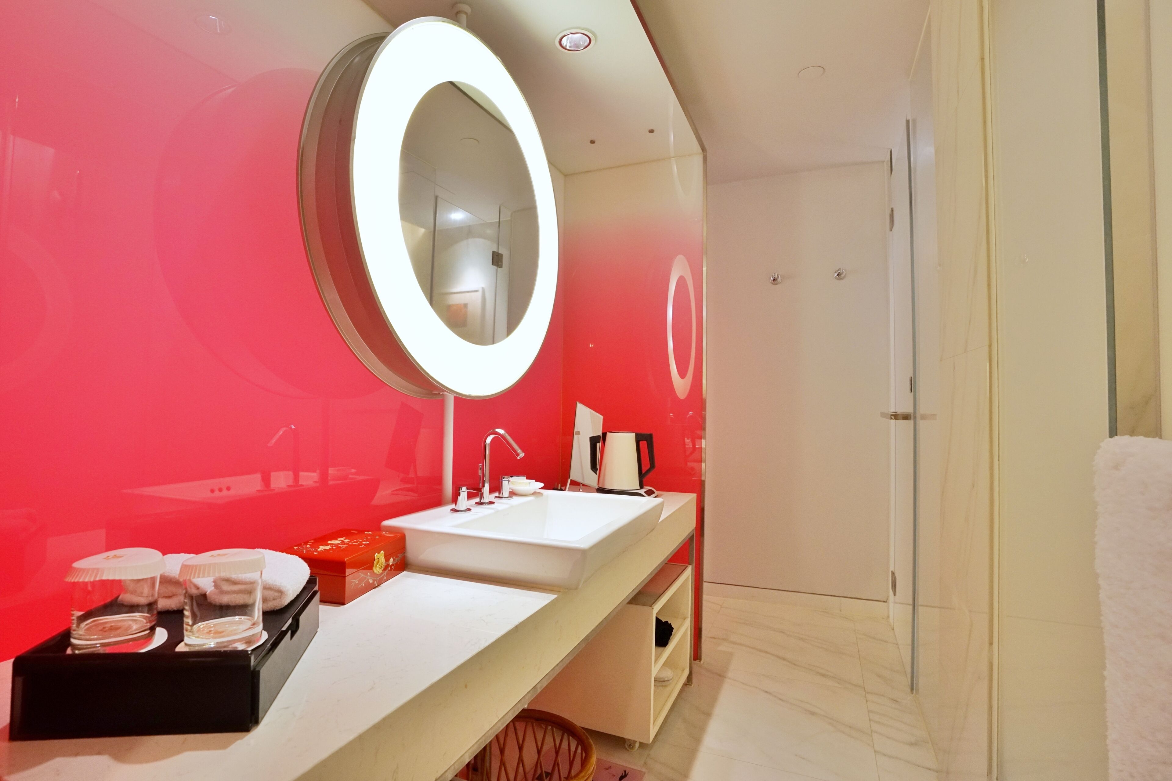 Une salle de bain moderne avec un grand miroir, un lavabo blanc et un meuble-lavabo avec espace de rangement.