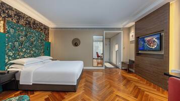 Una habitación de hotel moderna con una cama grande, un televisor montado en la pared y un suelo de madera con patrón de espiga.