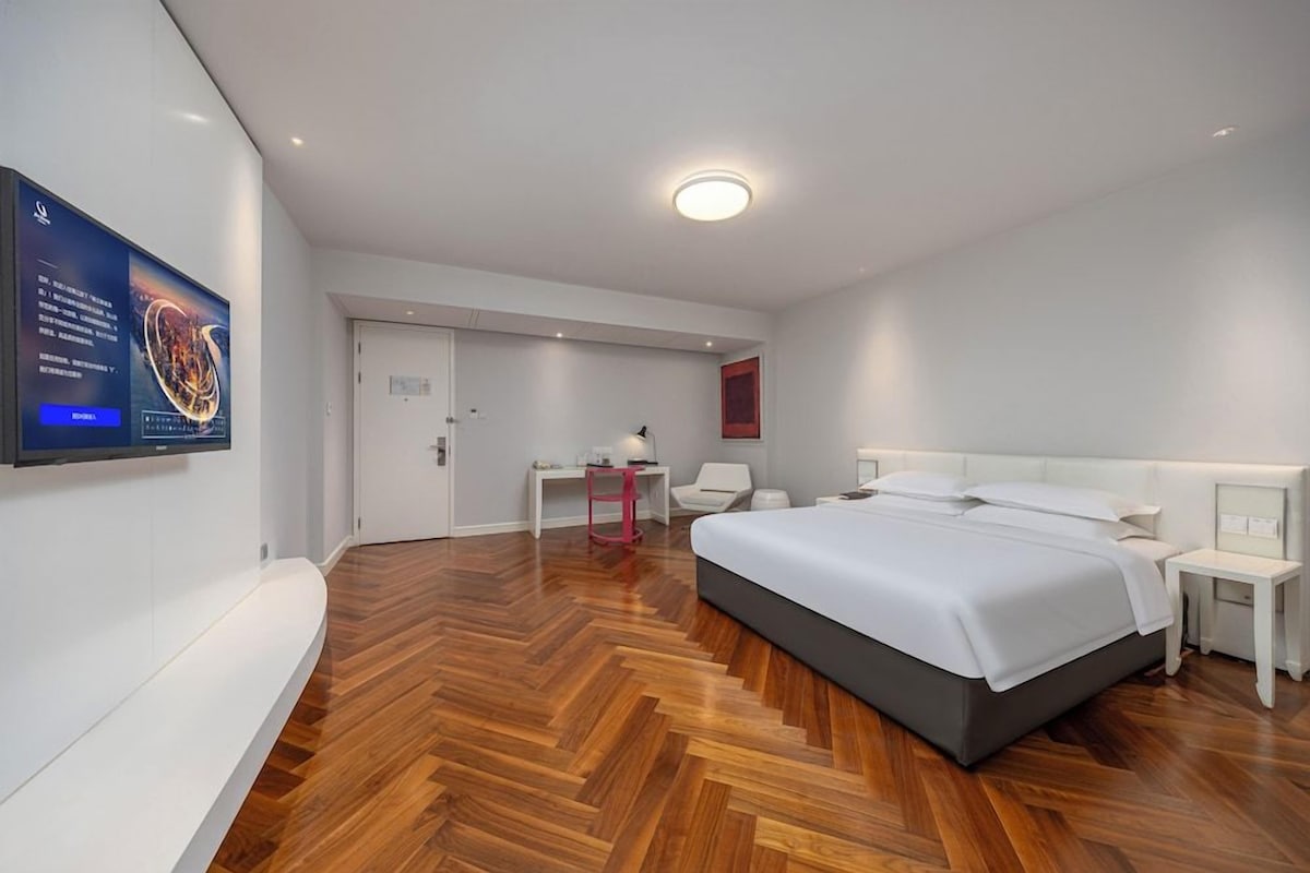 Una habitación de hotel moderna con una cama grande, un escritorio y una silla.