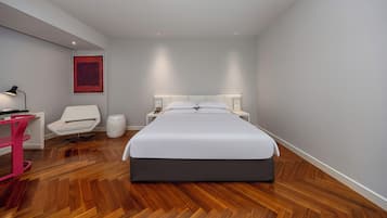 Un dormitorio moderno con una cama grande, un escritorio, una silla y una mesita de noche.