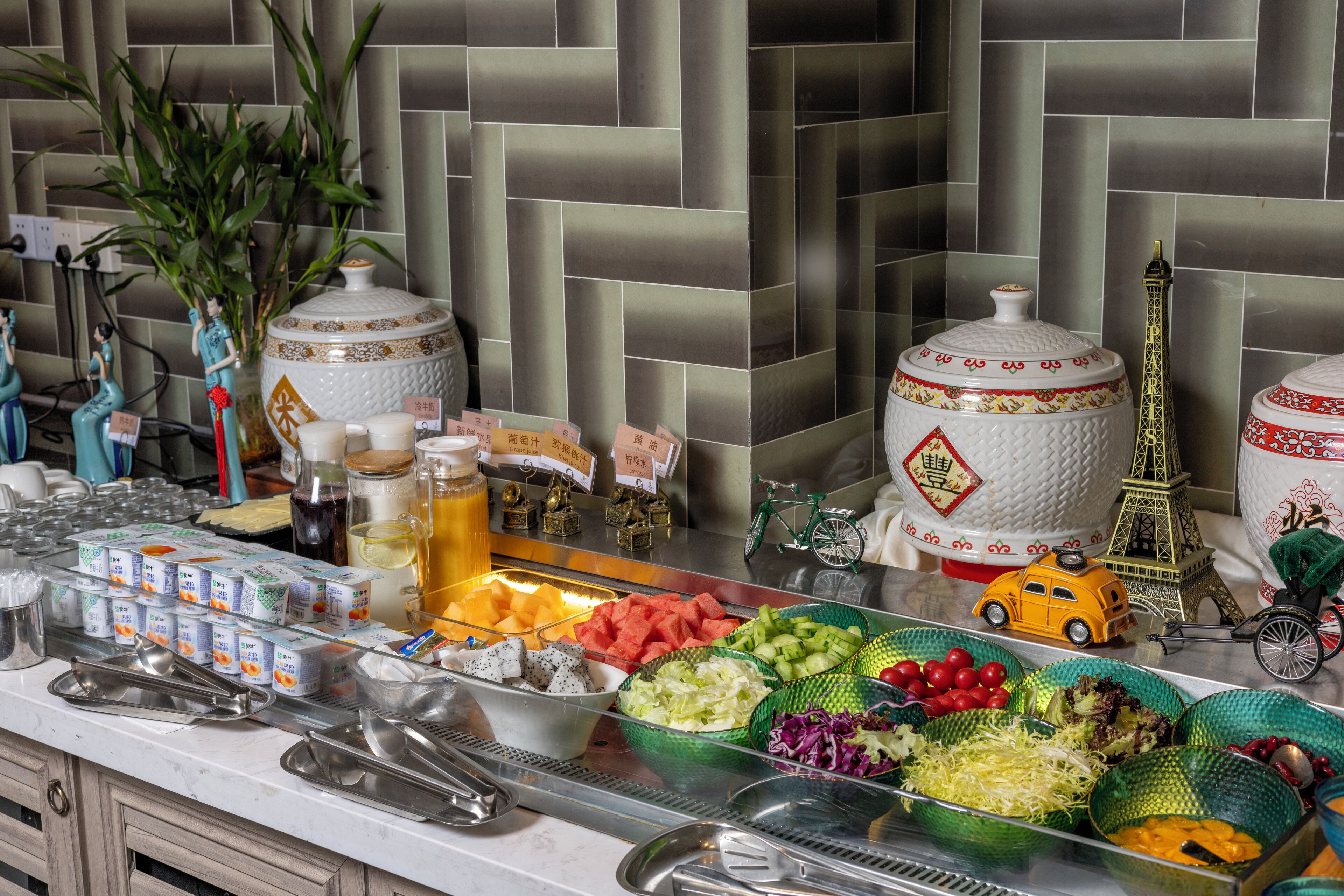 A buffet setup with various food items, decorative items, and a tiled wall in the background.