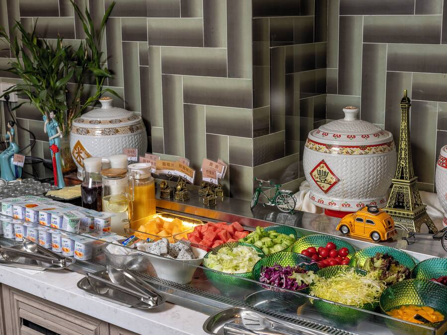 A buffet setup with various food items, decorative items, and a tiled wall in the background.