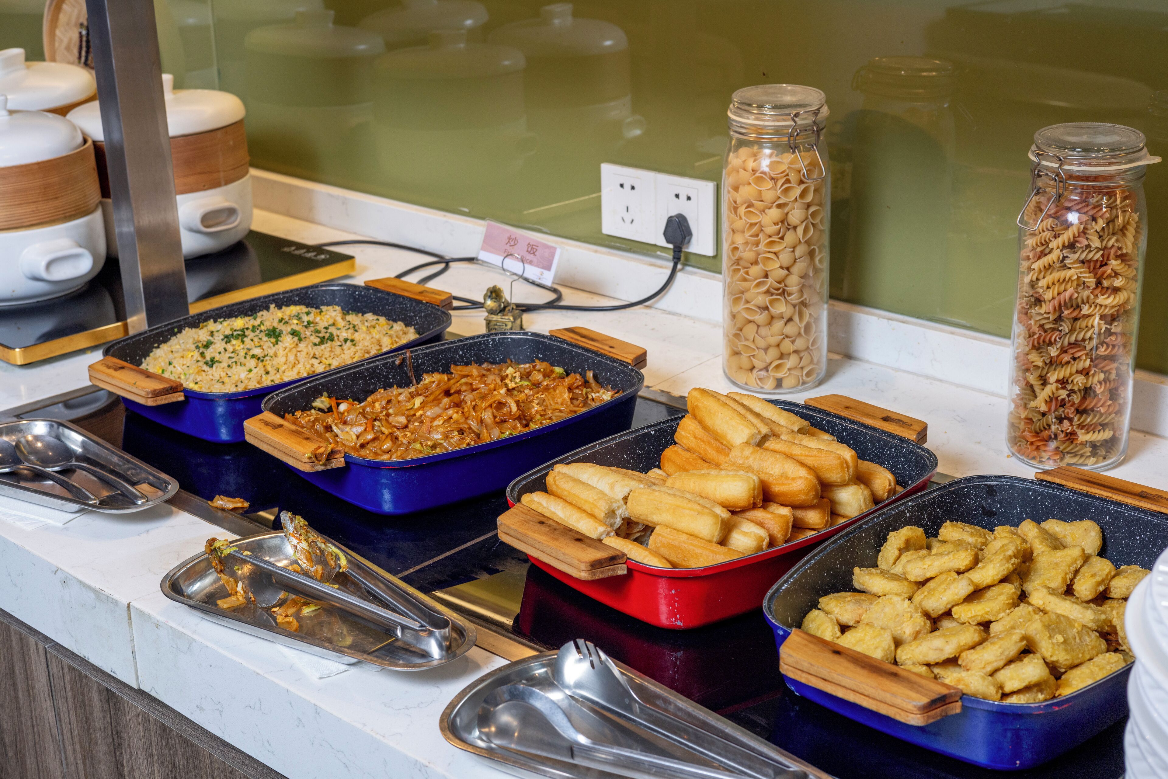 Un bufé con diversos platos, incluyendo arroz frito, pasta y otras opciones.
