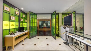 A hotel lobby with a reception desk, a glass display case, and a green-tinted wall with framed pictures. - Metropolo Dahua Hotel Shanghai (Shanghai)
