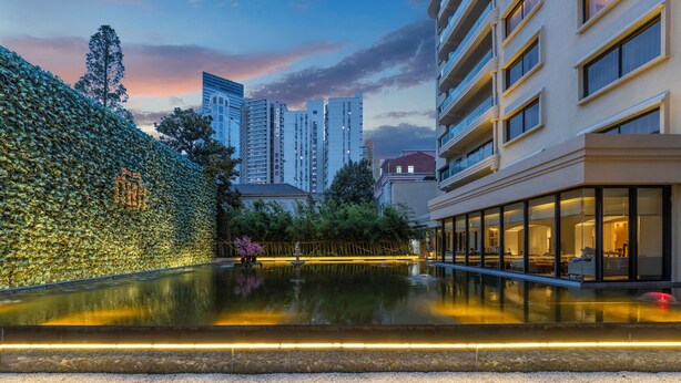 A modern hotel with a reflective pool, a bamboo wall, and high-rise buildings in the background. - Metropolo Dahua Hotel Shanghai (Shanghai)