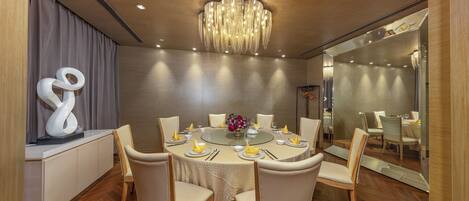 A modern dining room with a round table, white chairs, and a chandelier.