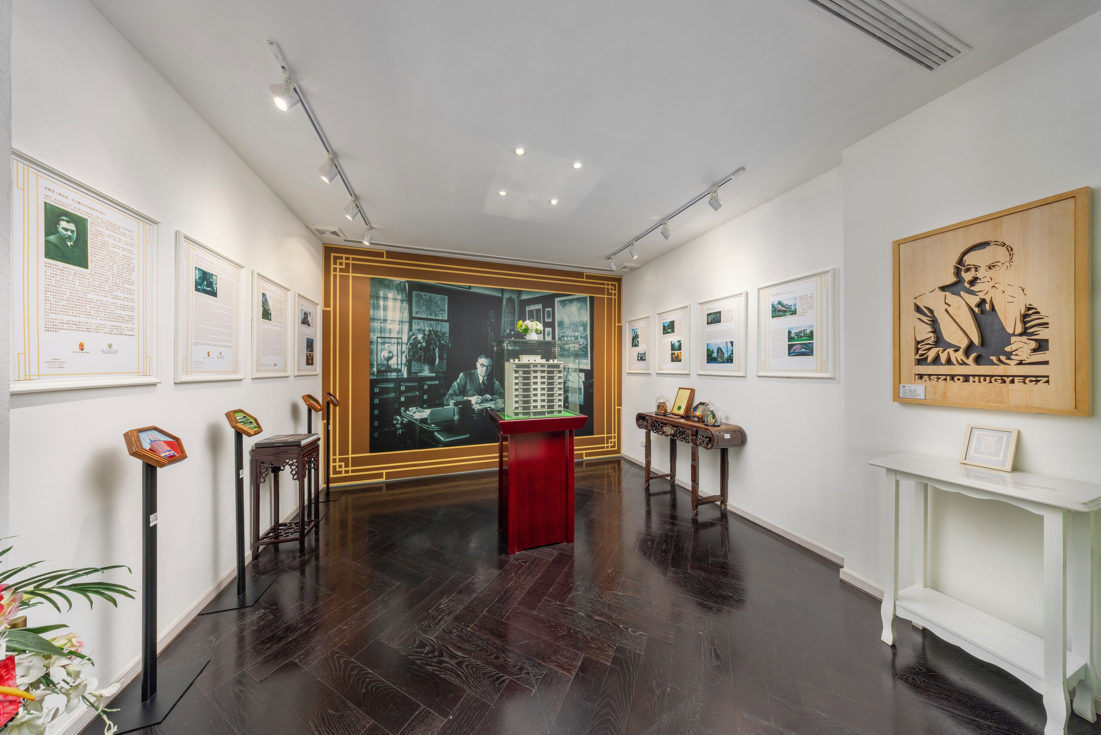 Una galería con obras de arte enmarcadas, placas informativas y una vitrina central.