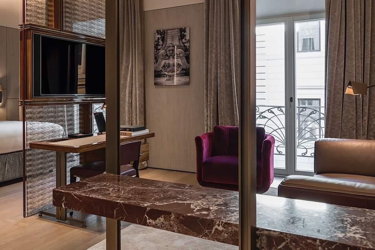 A hotel room with a bed, desk, chair, and a sofa.