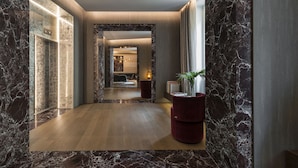 A modern hallway with marble walls, a wooden floor, and a red seating area. - Fendi Private Suites (Rome)